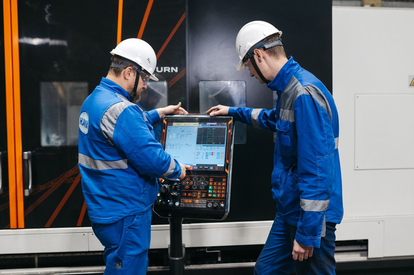 Industrial technicians checking CNC equipment for production matching